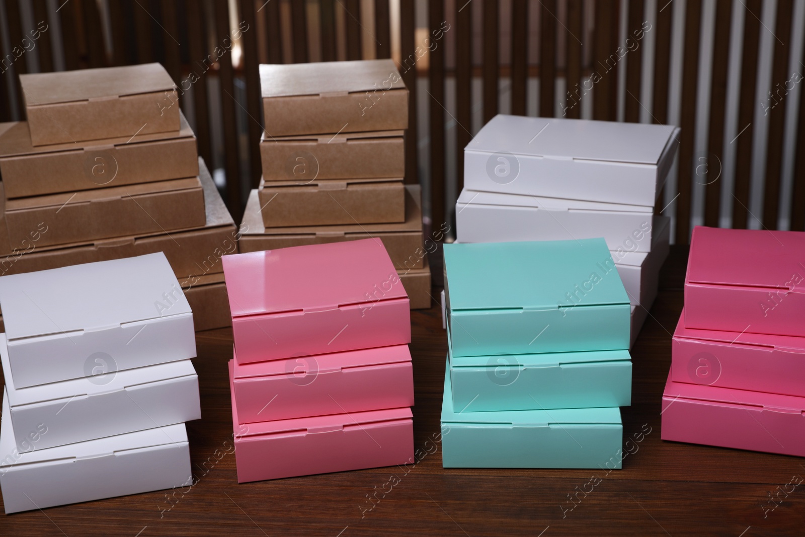 Photo of Stacked packaging boxes on wooden table indoors. Production line