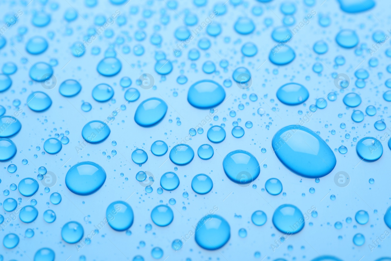 Photo of Water drops on light blue background, closeup view