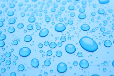 Photo of Water drops on light blue background, closeup view