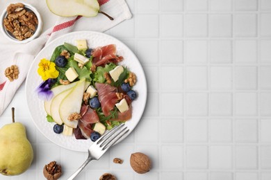 Photo of Tasty salad with brie cheese, prosciutto, walnuts and pear served on white tiled table, flat lay. Space for text