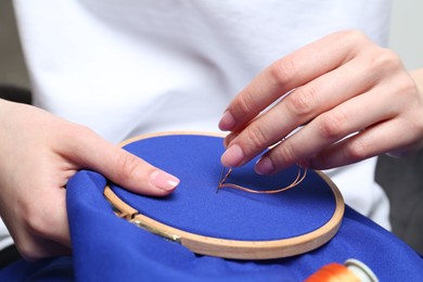 Woman with sewing needle and thread embroidering on cloth, closeup