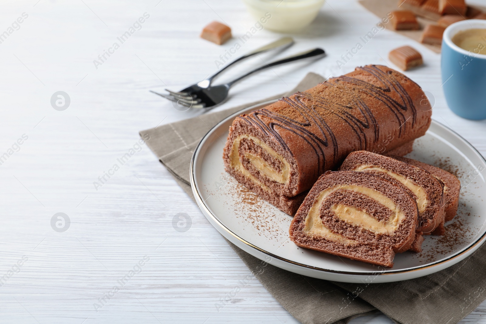 Photo of Tasty chocolate cake roll with cream on white wooden table, space for text