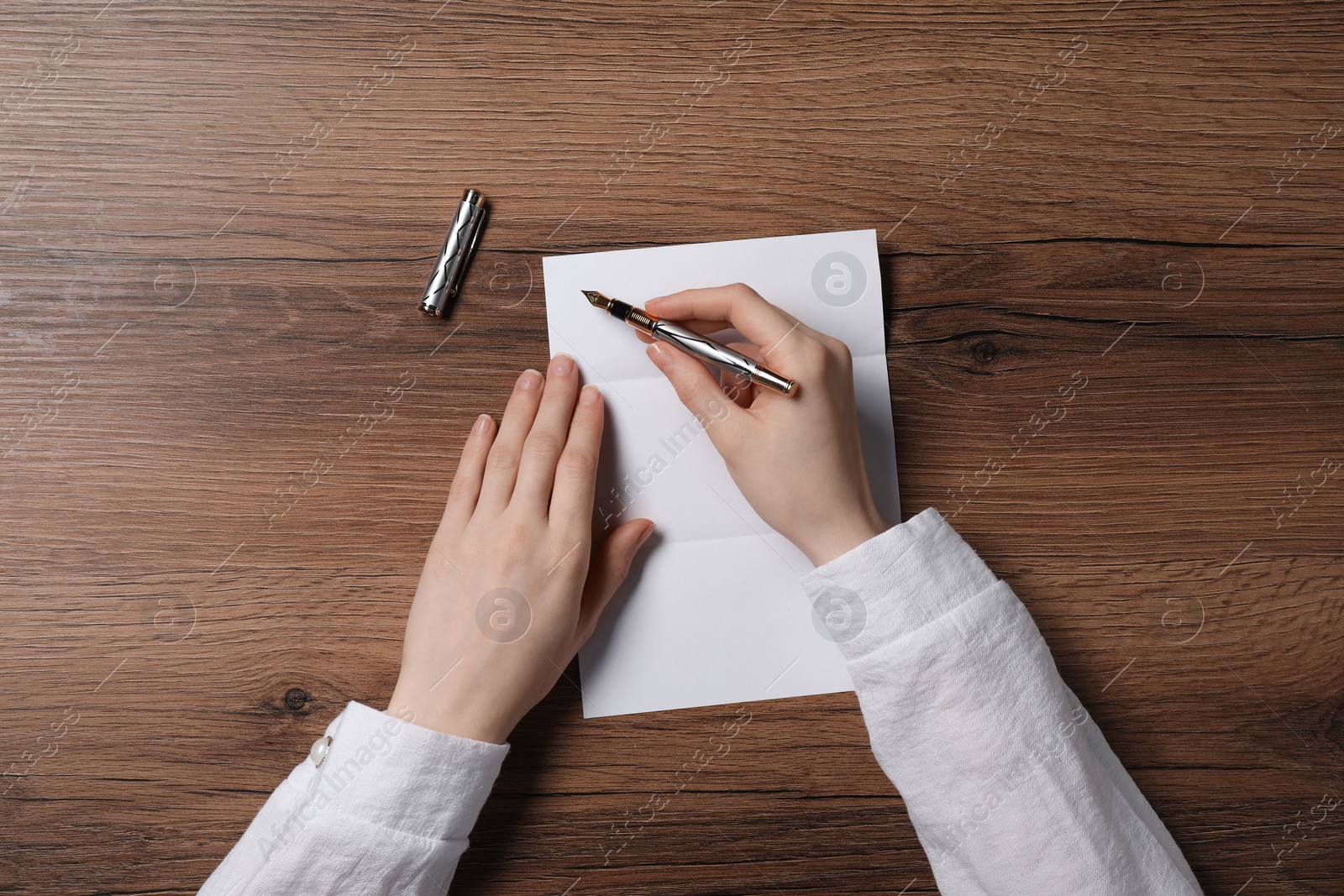 Photo of Woman writing letter at wooden table, top view