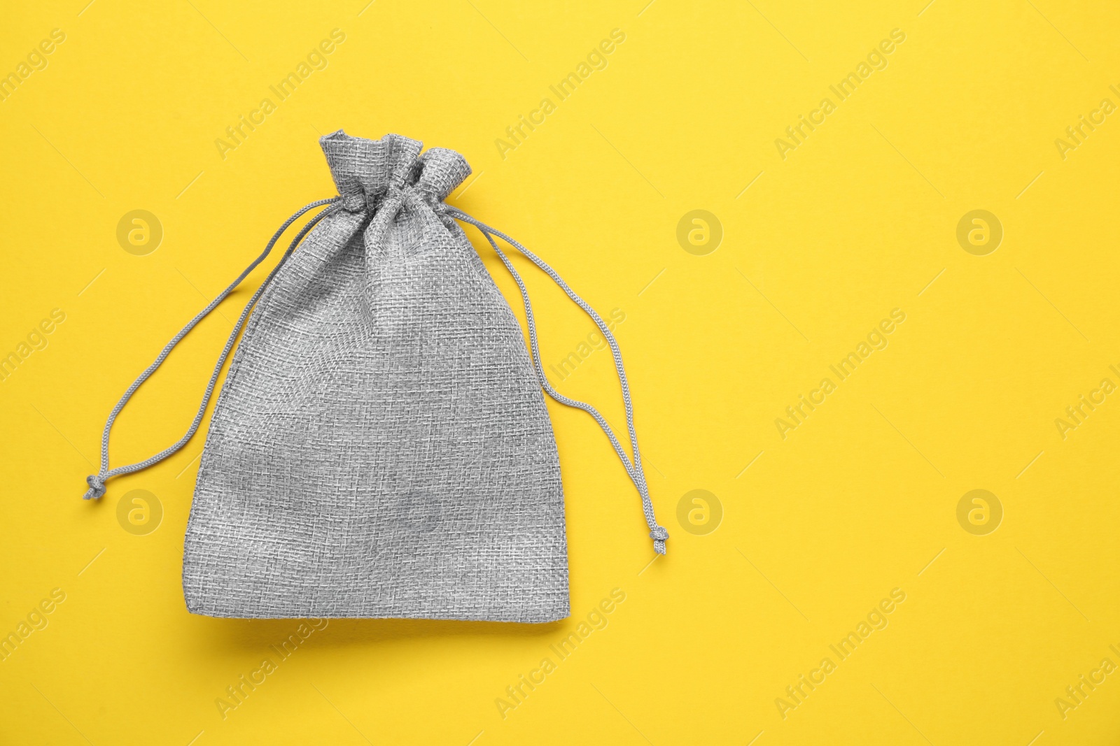 Photo of Violet burlap bag on yellow background, top view. Space for text