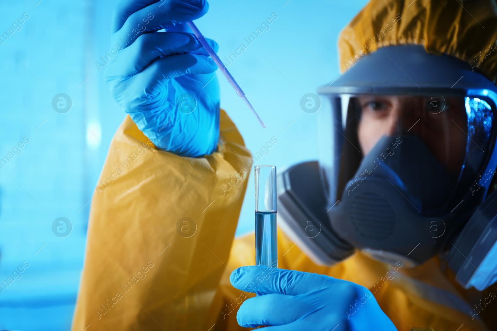 Photo of Scientist in chemical protective suit dripping reagent  into test tube at laboratory, focus on hands. Virus research