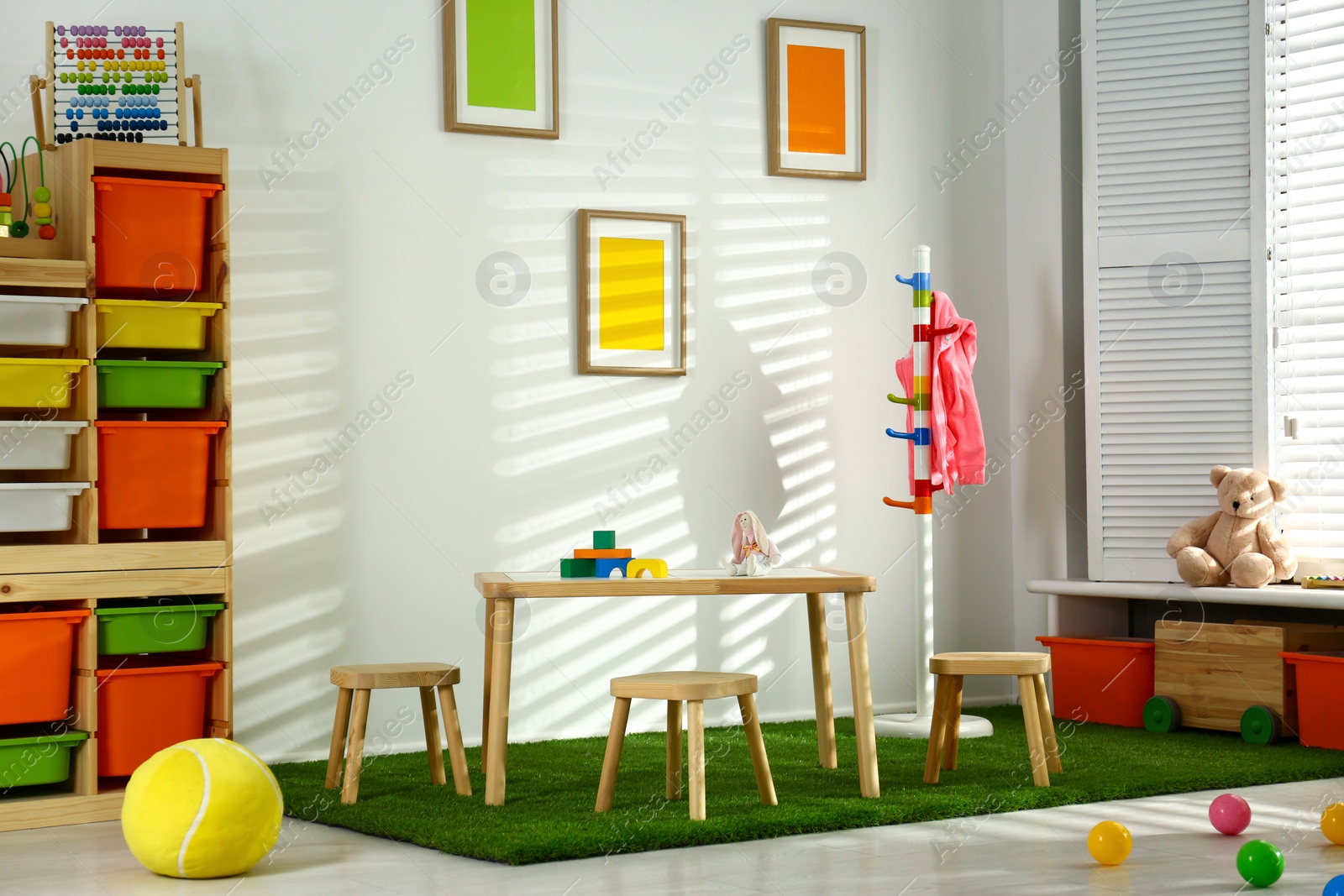 Photo of Stylish playroom interior with wooden table and stools