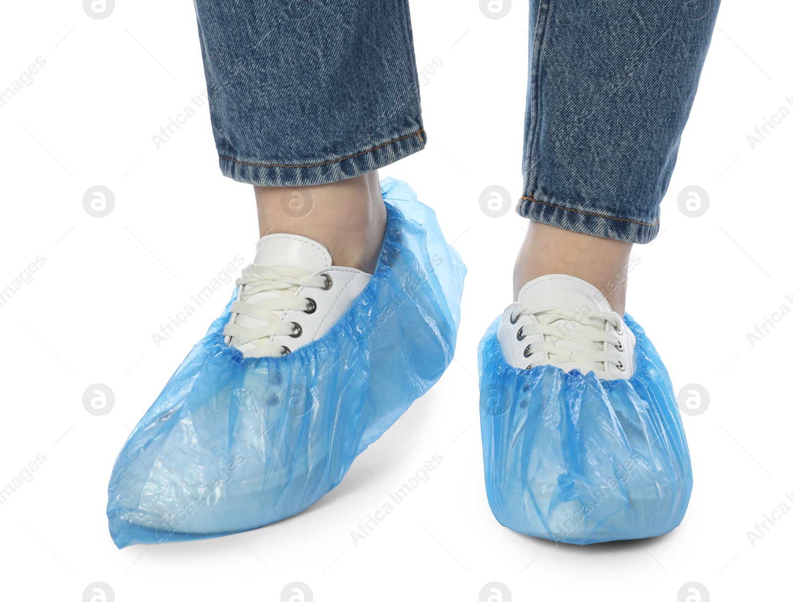 Photo of Woman wearing blue shoe covers onto her sneakers against white background, closeup