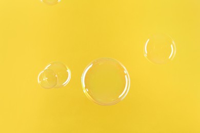 Photo of Beautiful transparent soap bubbles on yellow background