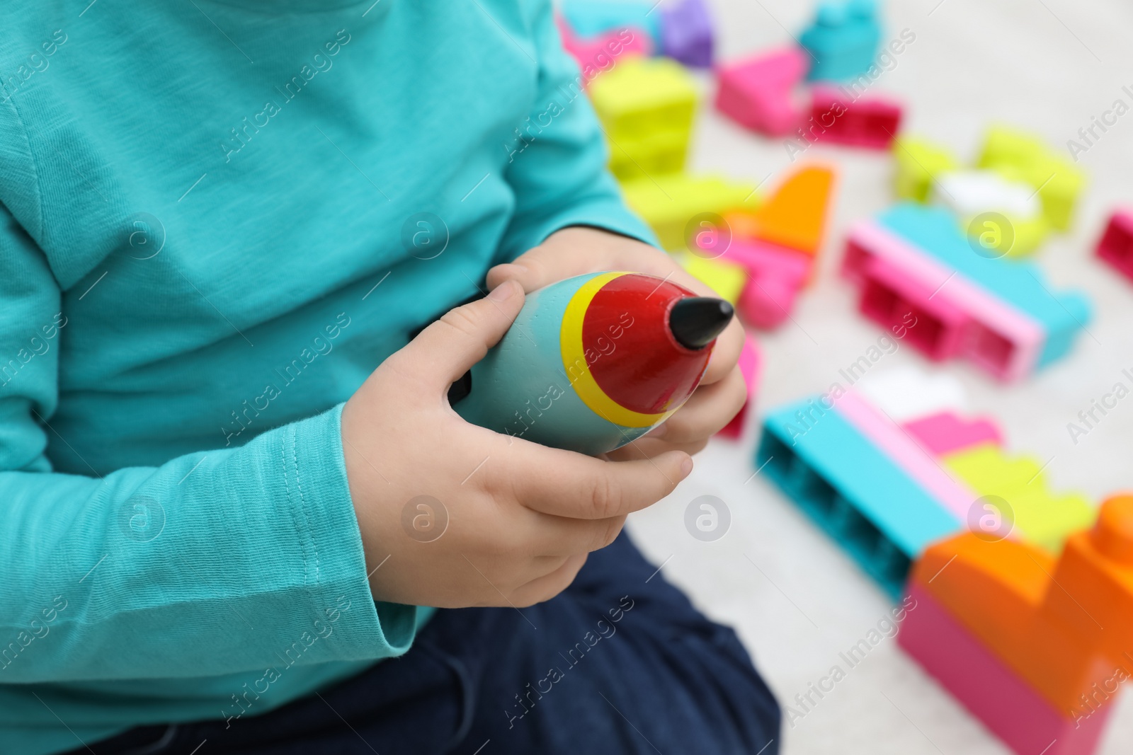 Photo of Little child playing with toy rocket indoors, closeup