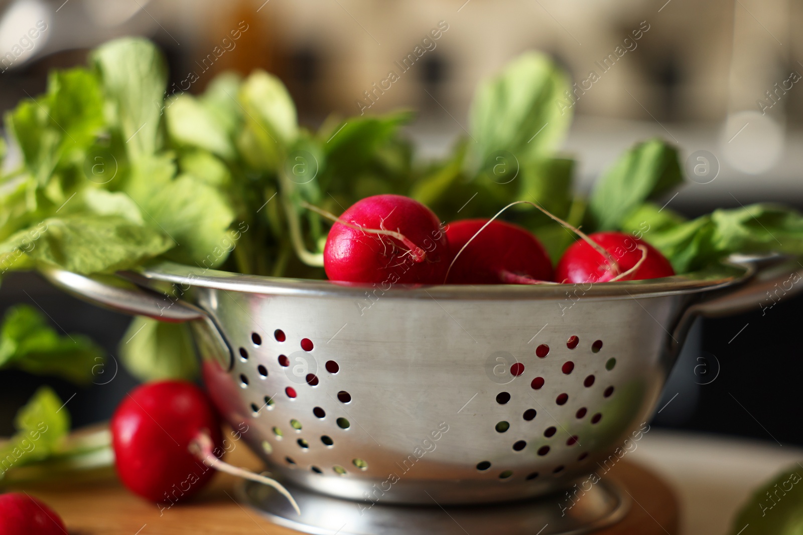 Photo of Metal colander with fresh radishes on table, closeup