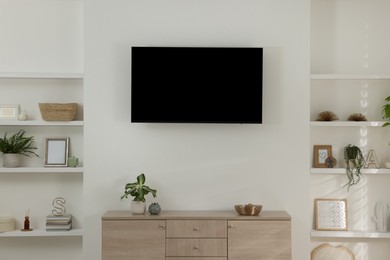 Stylish TV set mounted on wall in room