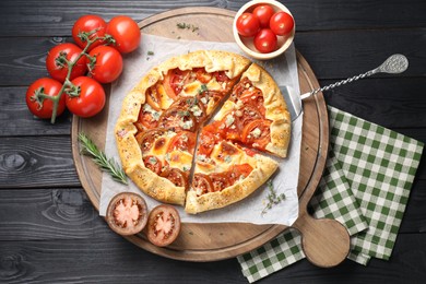 Photo of Tasty galette with tomato and cheese (Caprese galette) on black wooden table, top view