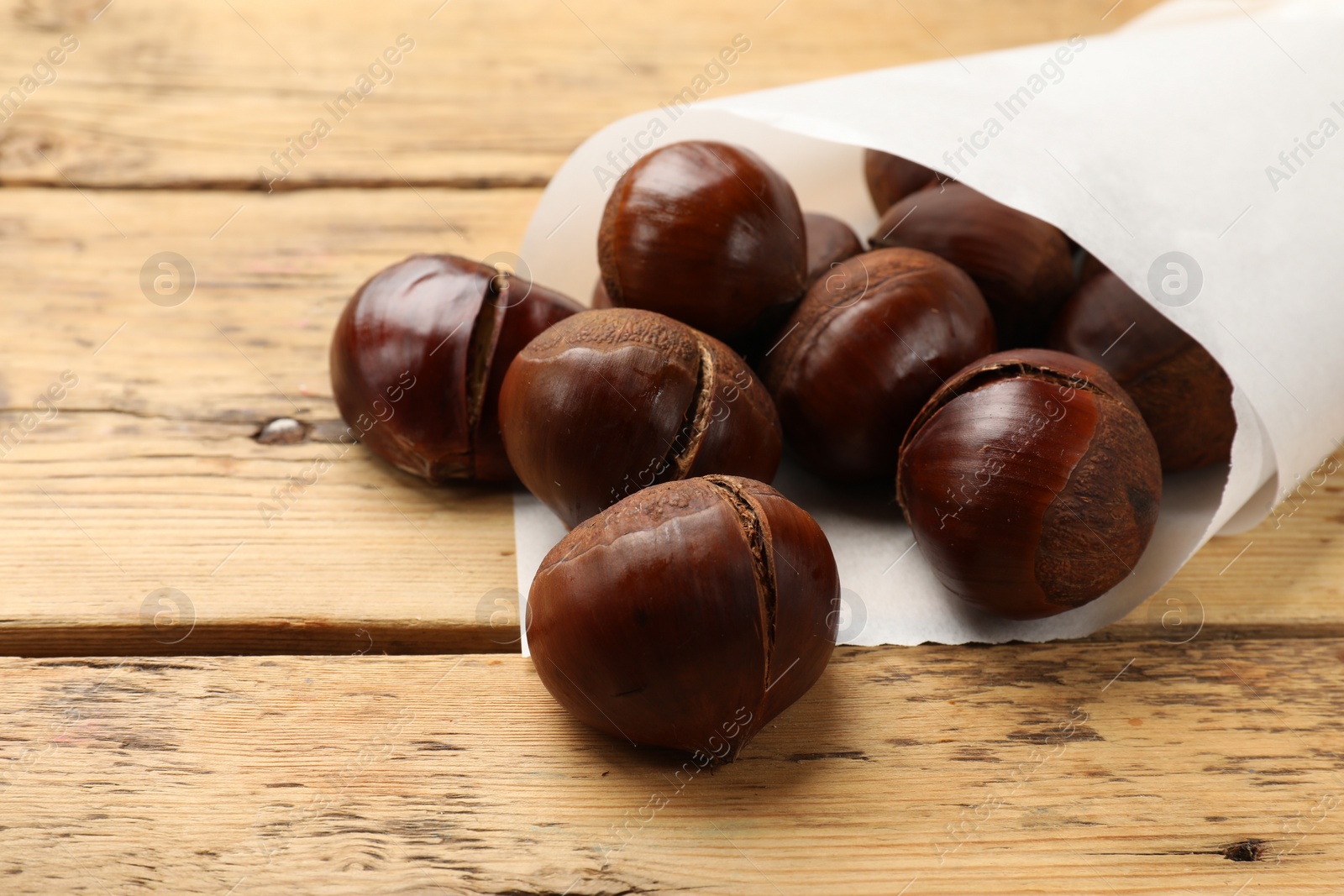 Photo of Fresh edible sweet chestnuts on wooden table, closeup