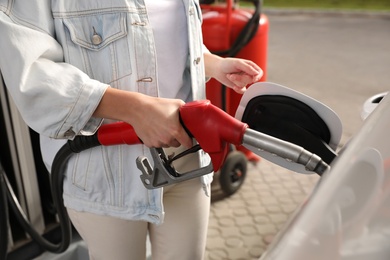 Woman refueling car at self service gas station, closeup