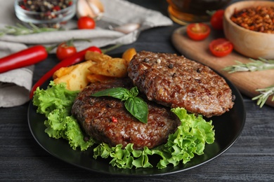 Photo of Grilled meat cutlets for burger on black wooden table