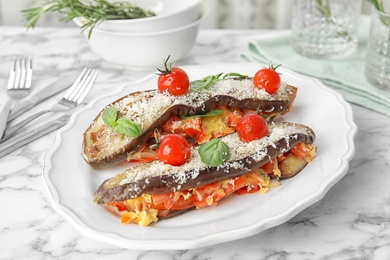 Photo of Baked eggplant with tomatoes, cheese and basil on marble table