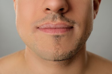 Photo of Man with half shaved face on grey background, closeup