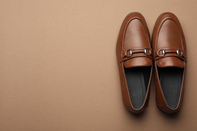 Photo of Pair of stylish male shoes on brown background, top view. Space for text