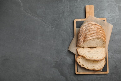 Photo of Board with cut bread on grey table, top view. Space for text