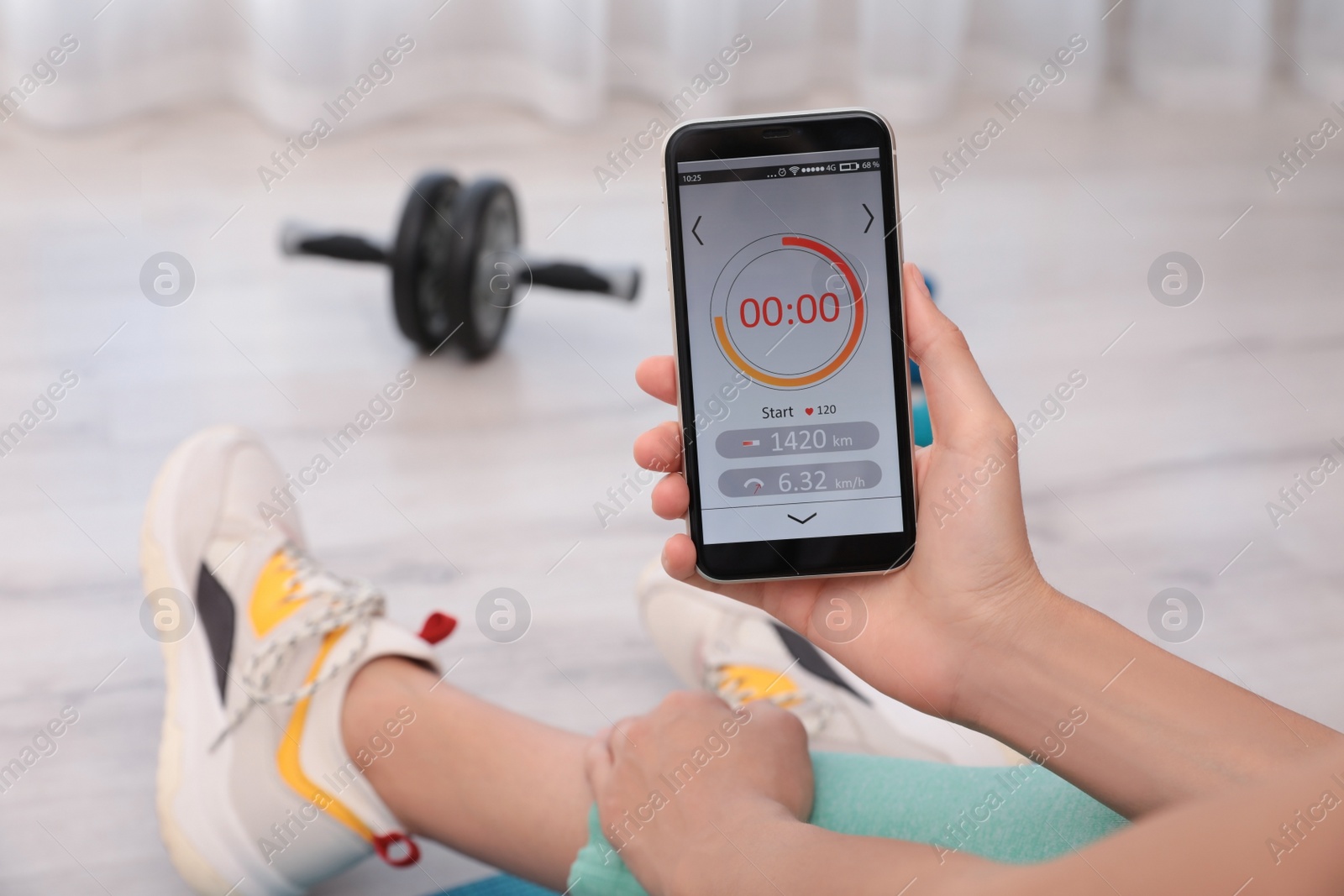 Photo of Young woman using fitness app on smartphone indoors, closeup