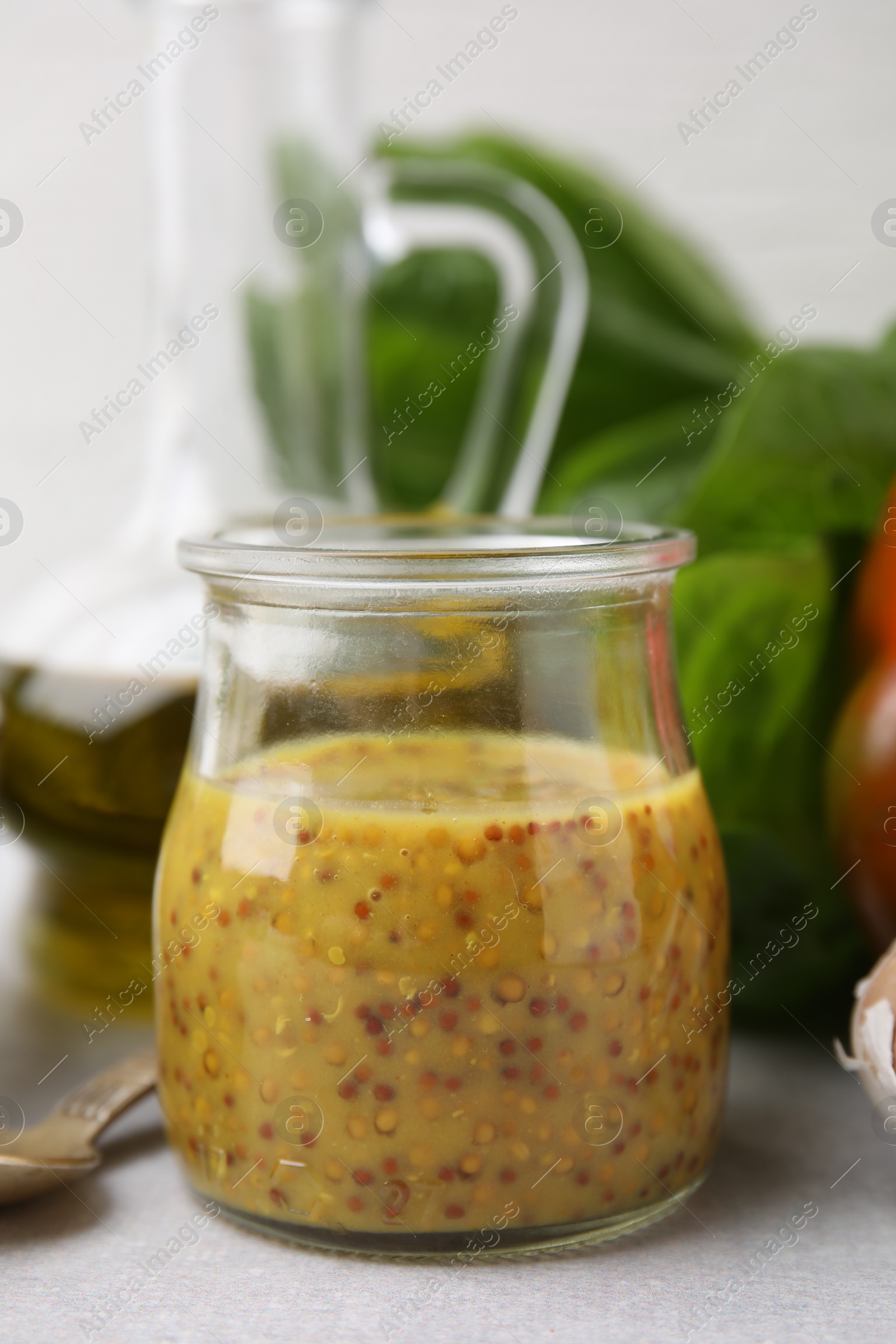 Photo of Tasty vinegar based sauce (Vinaigrette) in jar on light table, closeup