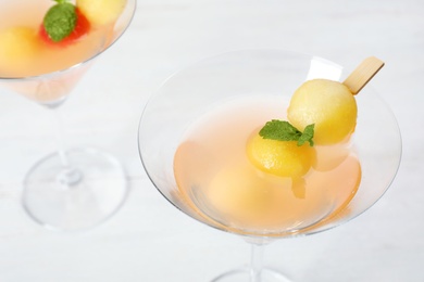 Glass with tasty melon ball drink on light background, closeup