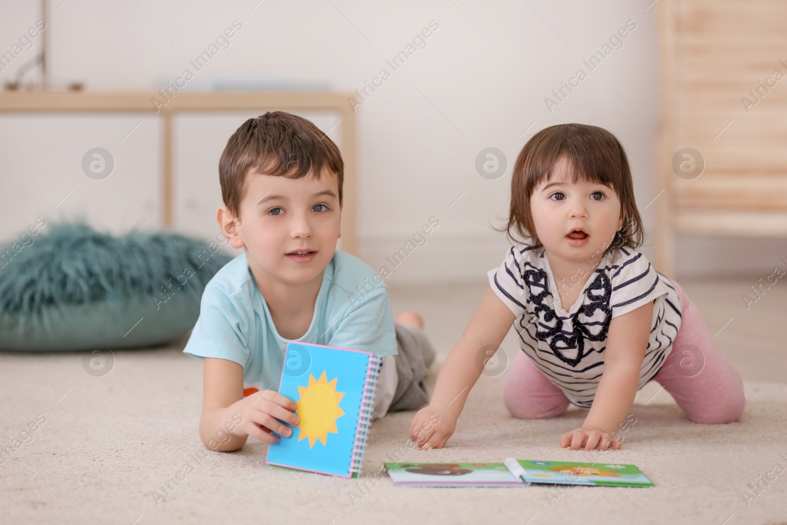 Photo of Cute little boy spending time with his baby sister at home