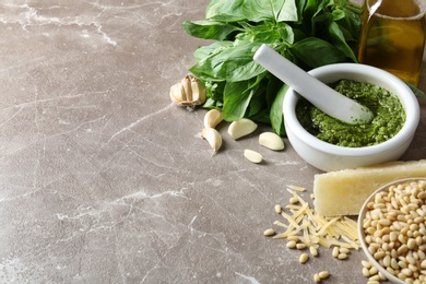 Photo of Composition with pesto sauce in mortar and ingredients on table. Space for text