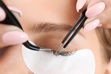 Young woman undergoing eyelash extensions procedure, closeup