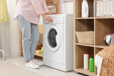 Woman near washing machine in laundry room, closeup