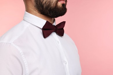 Photo of Man in shirt and bow tie on pink background, closeup