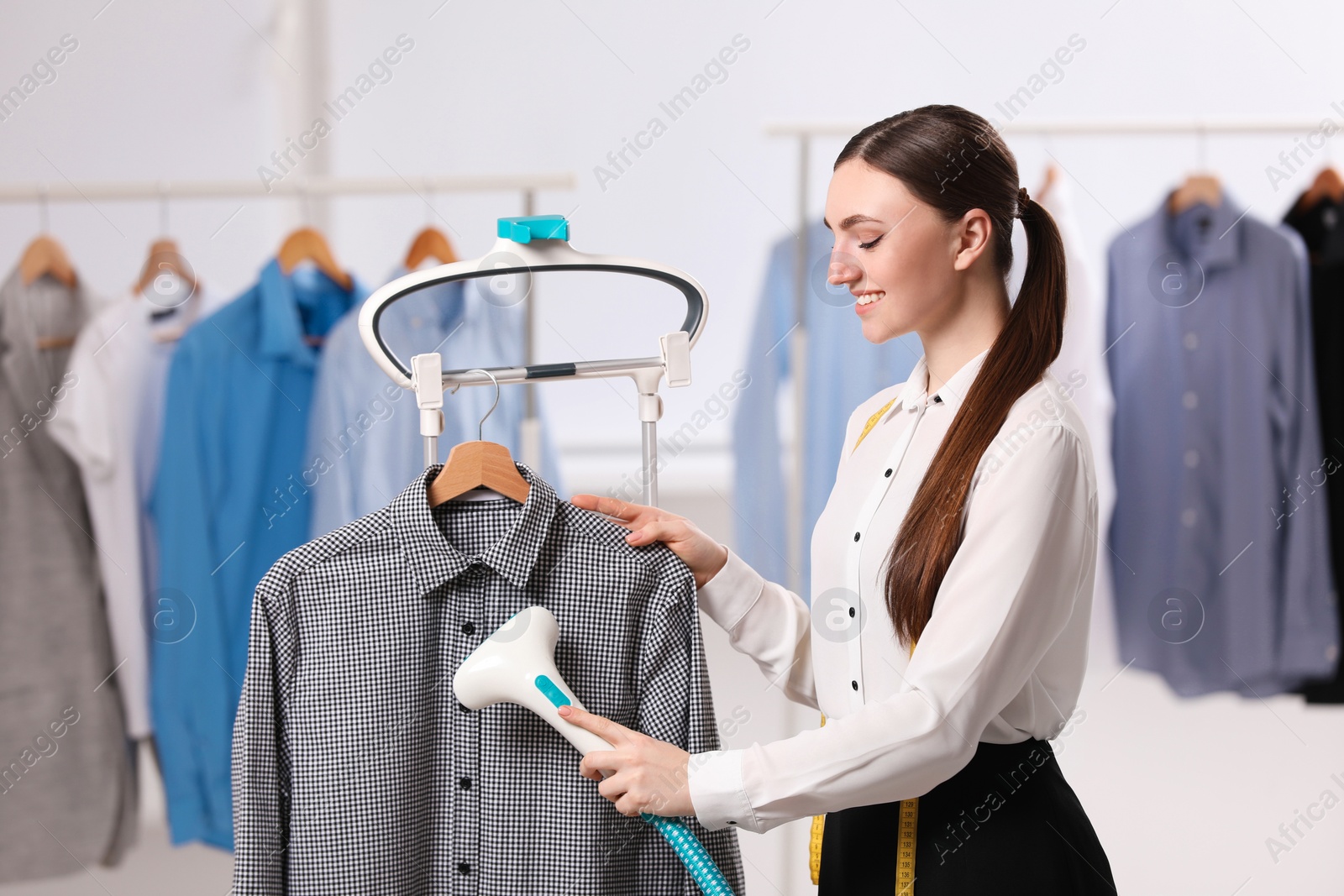 Photo of Woman steaming shirt on hanger in room