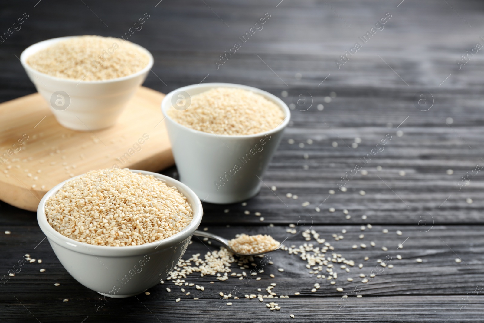 Photo of Sesame seeds on black wooden table. Space for text