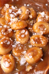 Photo of Tasty candies, caramel sauce and salt as background, closeup