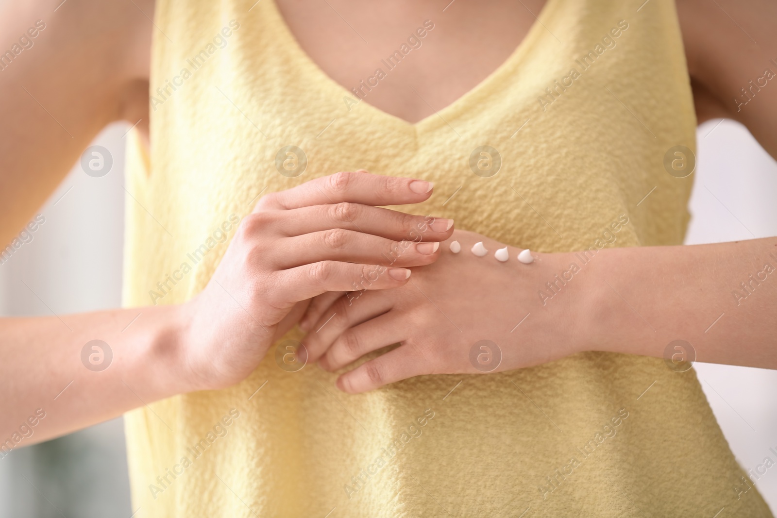 Photo of Young woman applying hand cream, closeup