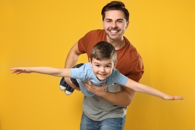 Photo of Portrait of dad playing with his son on color background