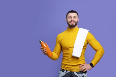 Handsome man with thermo bottle and towel on purple background, space for text