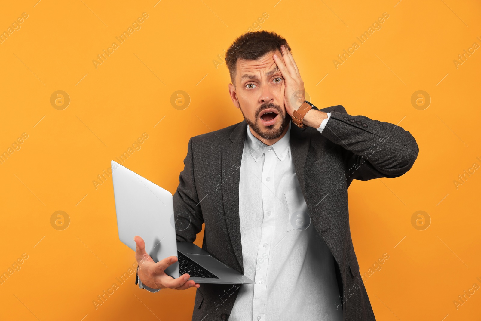 Photo of Emotional man with laptop on orange background. Being late concept