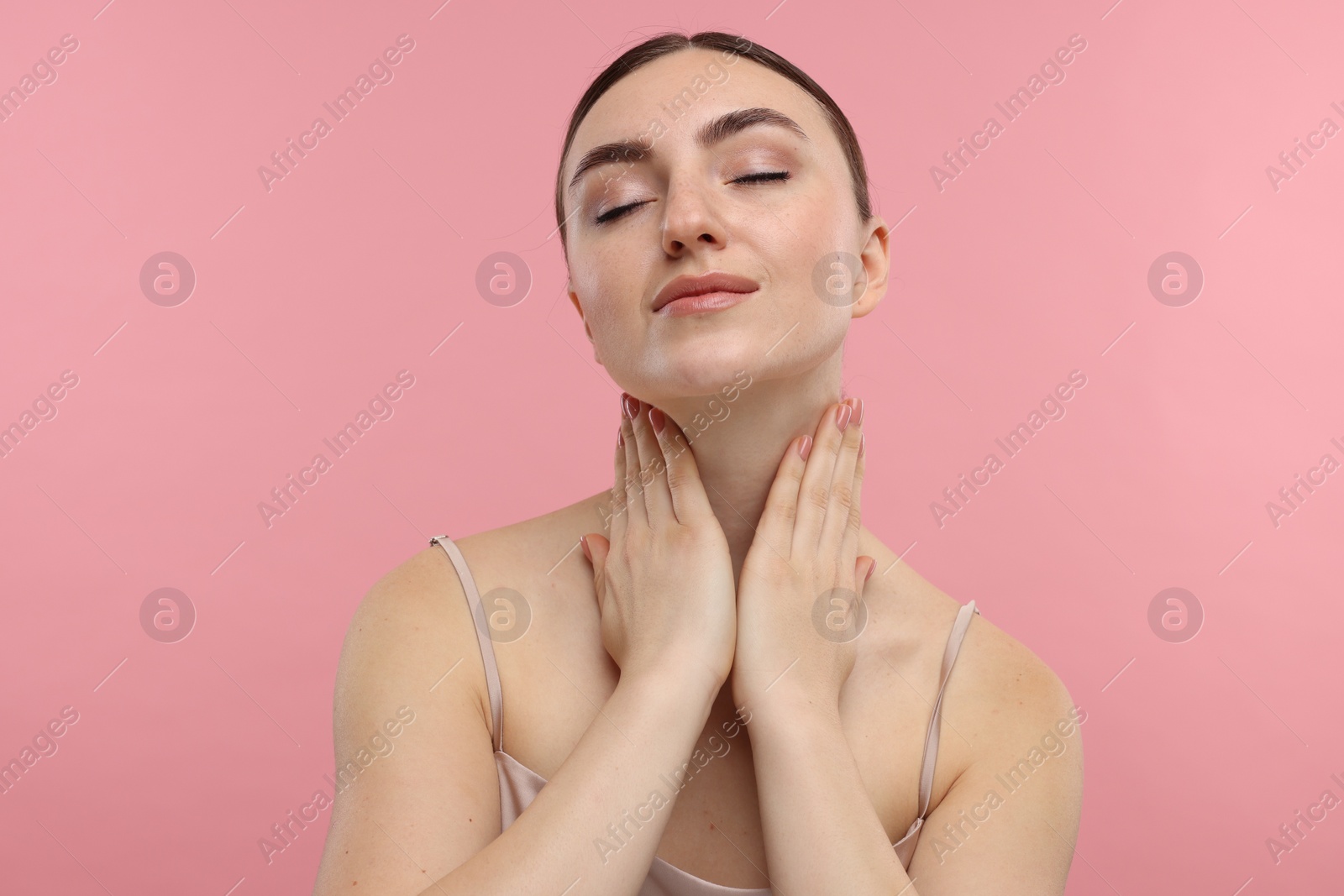 Photo of Beautiful woman touching her neck on pink background