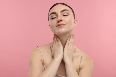 Beautiful woman touching her neck on pink background