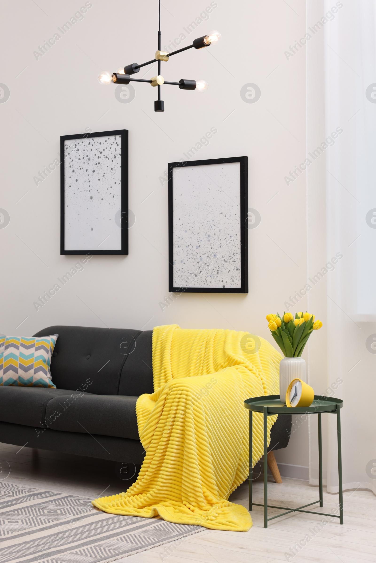 Photo of Spring atmosphere. Stylish living room interior with comfortable furniture and bouquet of beautiful yellow tulips