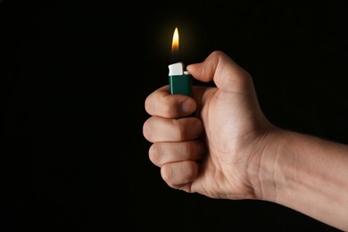 Photo of Man holding green lighter on black background, closeup
