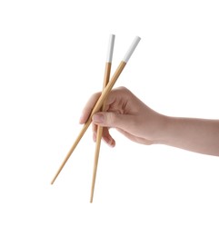 Woman holding pair of wooden chopsticks on white background, closeup