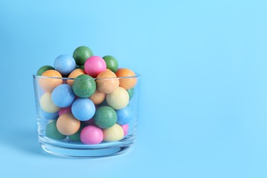 Bowl with bright gumballs on light blue background. Space for text