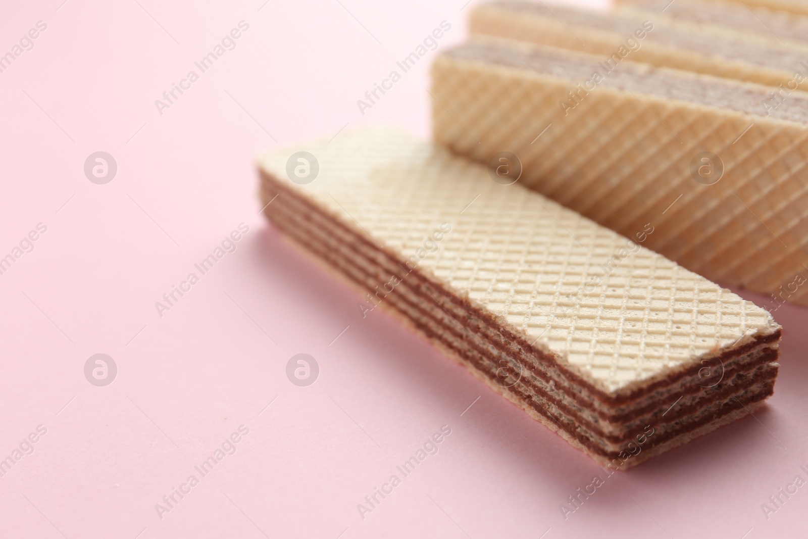 Photo of Tasty wafer sticks on pink background, closeup with space for text. Sweet food