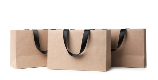 Photo of Paper shopping bags with ribbon handles on white background. Mockup for design