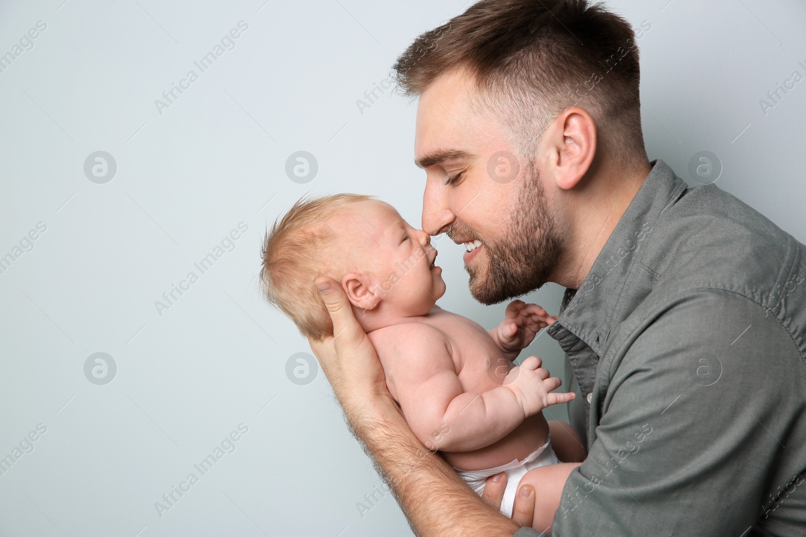 Photo of Father with his newborn son on light grey background