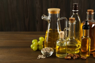 Vegetable fats. Different oils in glass bottles and ingredients on wooden table, space for text