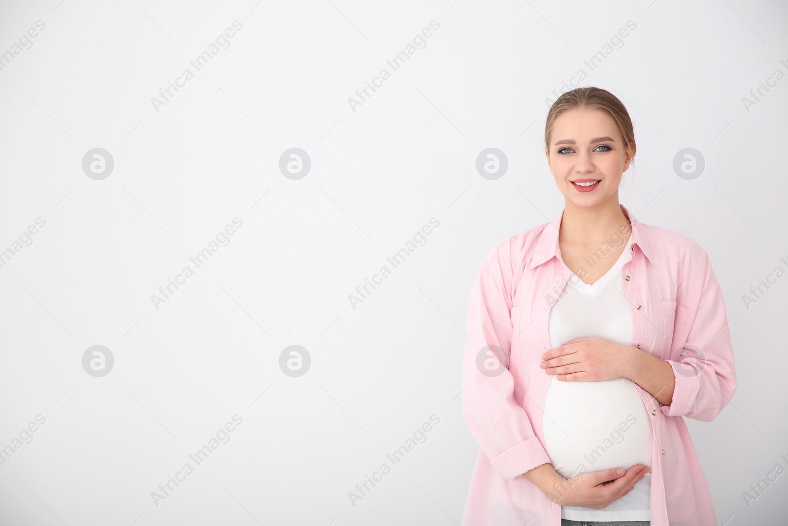 Photo of Young pregnant woman on white background. Space for text