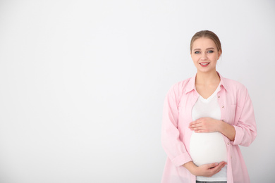 Photo of Young pregnant woman on white background. Space for text